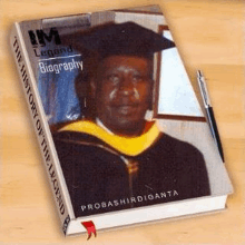 a book with a picture of a man in a graduation cap and gown is sitting on a wooden table .