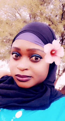 a woman wearing a hijab has a pink flower on her forehead