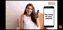 a woman is smiling while holding a phone with the words top song on your playlist on the screen