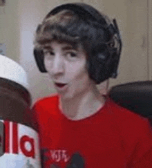 a young man wearing headphones is holding a giant jar of nutella .