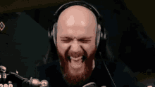 a bald man with a beard is wearing headphones and making a face .