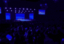 a blurred image of a crowd at a concert with a blue light behind them