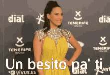 a woman in a yellow dress is standing on a red carpet in front of a sign that says tenerife