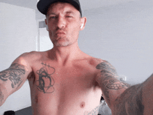 a shirtless man with tattoos on his chest and arms takes a picture