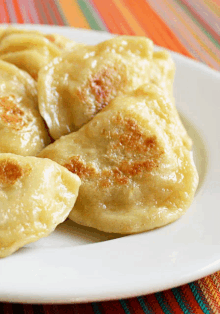 a white plate topped with fried dumplings sits on a colorful table cloth