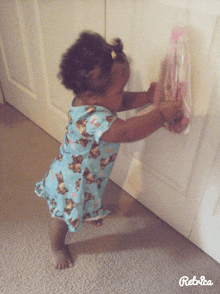 a little girl in a blue bear print dress reaches for a pink bag