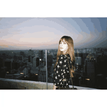 a woman stands on a balcony overlooking the city