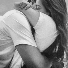 a black and white photo of a woman kissing a man on the cheek .