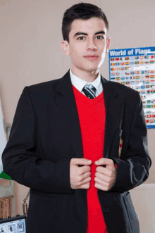 a young man in a suit stands in front of a world of flags display