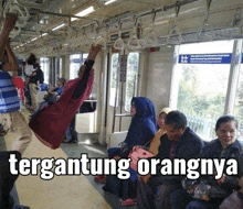 a woman is hanging upside down on a subway train .