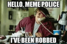 a man is sitting at a desk talking on a phone and says `` hello meme police i 've been robbed ''