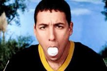 a man in a black and yellow jersey is blowing bubble gum in his mouth .