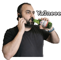 a man with a beard is drinking from a bottle and talking on a cell phone