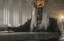 a man with dreadlocks sits at a table with a hat on