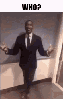 a man in a suit and tie is standing in a hallway with his arms outstretched and smiling .