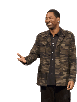 a man wearing a camo jacket and a black shirt is smiling