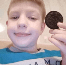 a young boy is holding a oreo cookie in his hand .