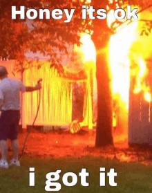 a man spraying a fire with a hose with the words honey it 's ok i got it