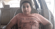 a young boy wearing a pink shirt that says chase your dreams