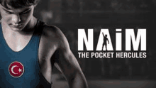 a young wrestler in a blue tank top is standing in front of a sign that says naim the pocket hercules .