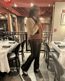 a woman stands in a restaurant with a red exit sign above her head