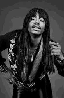 a black and white photo of a man with long hair and dreadlocks .