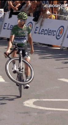 a man is riding a bike on a street in front of a sign that says e.leclerc on it .