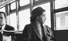 a black and white photo of rosa parks riding a bus with a man .