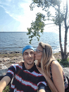 a woman kisses a man on the cheek in front of the water