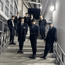 a group of young men in suits and ties are standing on stairs .