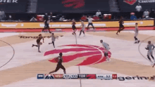 a basketball game is being played on a court with a toronto raptors logo on the court