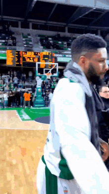 a basketball player stands on a court with a scoreboard behind him that shows a score of 7 to 3