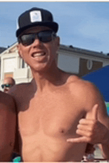 a shirtless man wearing sunglasses and a black hat is giving a thumbs up .