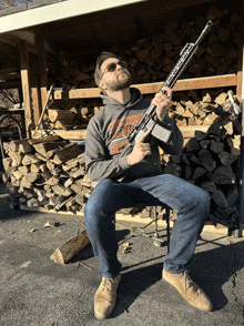 a man wearing a hoodie that says oregon on it holds a gun in front of a pile of logs