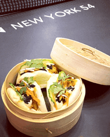 a bamboo steamer filled with food sits on a table with the word new york 54 on it