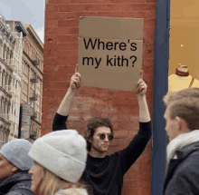 a man holds up a cardboard sign that says where 's my kith