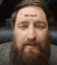 a man with a beard has a white sticker on his forehead that says wit kont