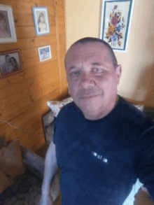 a man is taking a selfie in front of a wooden wall with pictures on it