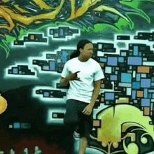 a man is dancing in front of a wall with graffiti on it .