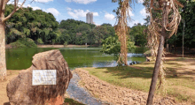 a large rock with a plaque on it sits in front of a lake in a park