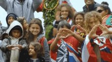 a group of children are making a heart shape with their hands and one of them is wearing a shirt that says uk on it