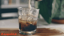 a glass of iced coffee is being poured with esquire printed on the bottom