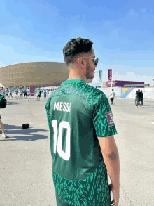 a man wearing a green shirt that says messi on the back