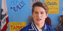 a young man in a blue jacket is standing in front of a wall with signs that say vote tammy