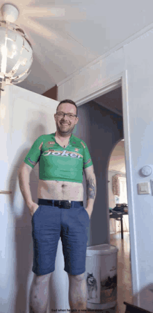 a man wearing a green joker shirt is standing in a hallway