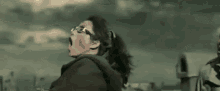 a woman wearing glasses is screaming in the air while standing on a roof .