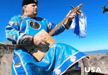 a man in a blue dress is playing a guitar and the word usa is on the bottom right