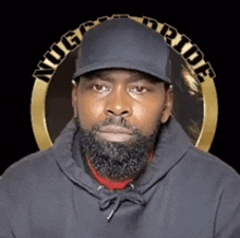 a man with a beard wearing a black hat and a hoodie with the word pride on it