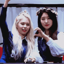 a woman with a flower crown on her head is standing next to another woman