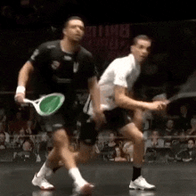 two men are playing squash in front of a crowd and a sign that says ' england ' on it